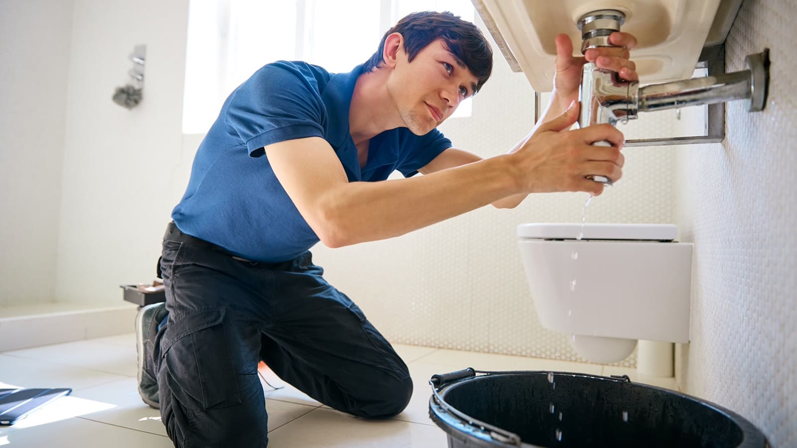 Plumber repairing a leaking bathroom sink drain